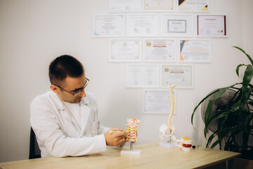Professional orthopedist at table in medical office