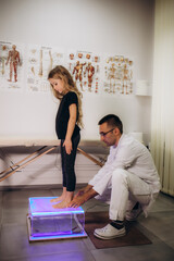 Close up of doctor checks child girl sitting on plantoscope by orthopedist. Kids examination...