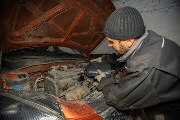A man pours new oil into an engine in a garage. A man in work gloves changes the engine oil in his car by pouring it into the engine. Thick oil flows into the engine in a golden stream.