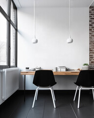 A minimalist dining room featuring a black table with four white chairs and two black pendant lights hanging from the ceiling. copy text