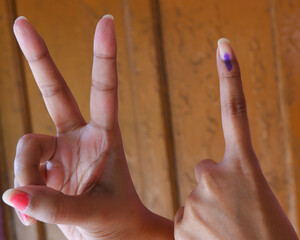 Ink on finger post casting vote in indian with victory sign.