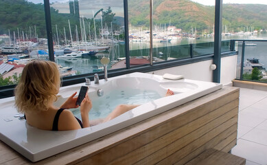 Young women chilling in outdoor hot tub. Luxury leisure activity in sea town
