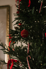 Beautiful New Year decor, the Christmas tree is decorated with red bows in the stylish interior of the living room