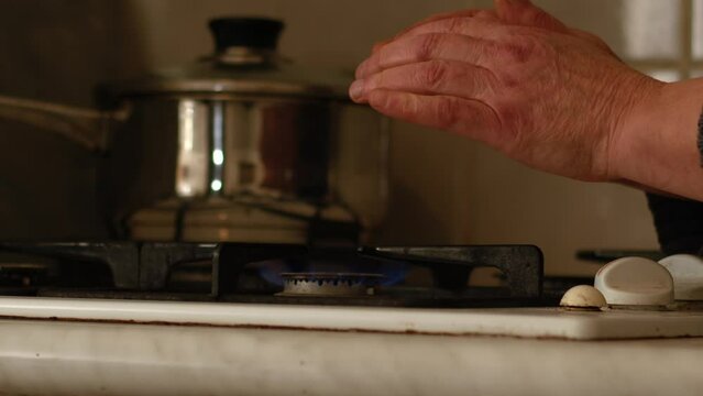 Hands warming on gas stove hob flames 