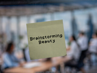 Post note on glass with 'Brainstorming Beauty'.