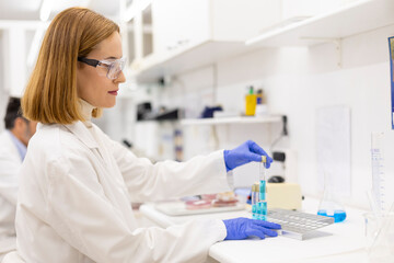 Lab technician pipetting blue solution in clinical analysis setting