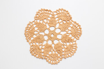 beige round crocheted napkin close-up on a white background. Crocheting as a hobby and way of...