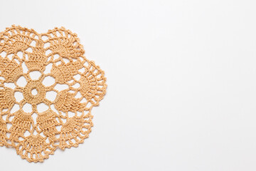 white background with crocheted beige doily on the side.