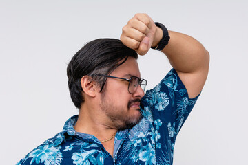 A man in a blue Hawaiian shirt, isolated on white, is humorously checking for underarm odor. Forgot...