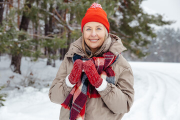 Smiling mature woman in red hat having hot tea outdoors