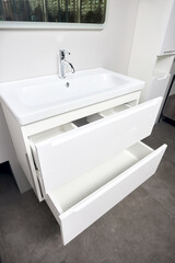 Bathroom with concrete wall stoneware tiled floor. White industrial flat loft bathroom with modern countertop basin ceramic sink and tap faucet, square mirror and wooden PVC drawer.