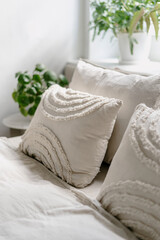 Fototapeta na wymiar Decorative linen cushions in boho style on comfort bed in cozy bedroom