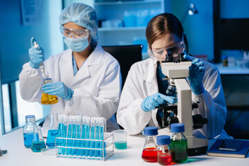 Young scientists conducting research investigations in a medical laboratory, a researcher in the foreground is using a microscope in laboratory