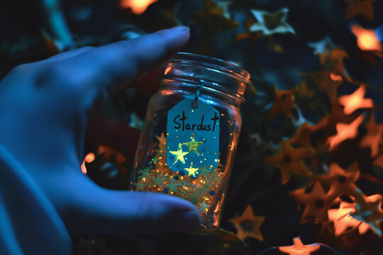 Hand holding a glass jar with christmas lights and stars on the background