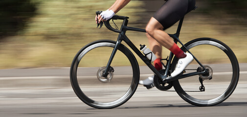 Motion blur of a bike race with the bicycle and rider at high speed. Professional male cyclist in racing outfit during a ride on bike outdoors. Panning technique used
