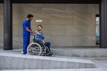 Dark-haired male nurse taking a patient in wheelchair for a walk