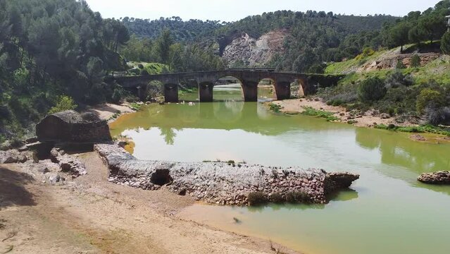 Watermill in the shore of Odiel river and roman bridge in the background in the hiking route of the water mills along the Odiel river from Sotiel Coronada, in Huelva province, Andalusia, Spain