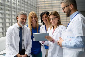 Group of doctors discussing test results, looking on tablet, medical team discussing patients...