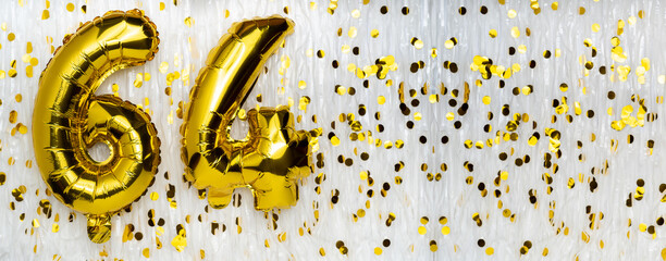 Golden foil balloon number, figure sixty-four on white with confetti background. 64th birthday...