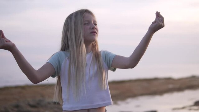 a young girl is standing on a beach with her arms outstretched
