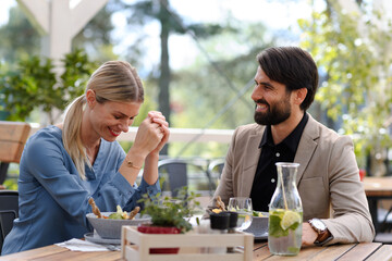Couple sitting outdoors on terrace restaurant, having dinner date. Business lunch for two managers, discussing new business project.