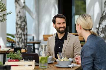Business lunch for two managers, discussing new business project. Couple sitting outdoors on terrace restaurant, having dinner date.