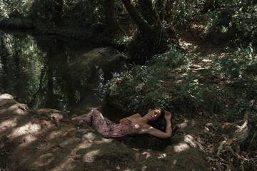 Woman rests meditating in the water in the river. Concept of spiritual connection with the natural environment and ethereal atmosphere between two worlds.