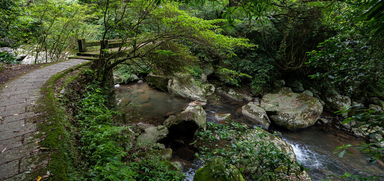 Little historic stone bridge across the river, stream go gently between huge rocks, hidden in the forest at the time of summer, in Yangmingshan National Park, Taipei, Taiwan.