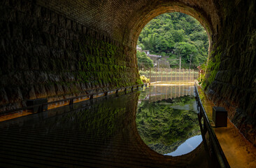 Abandoned tunnel turn into a tourism trail, in the entrance water reflect the scene outside, beautiful trace of time in the tunnel, in Sandiaoling, New Taipei City, Taiwan.