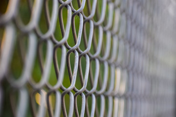 Chain link fence near the garden. Metallic fence.