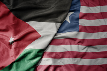big waving national colorful flag of liberia and national flag of jordan.