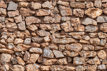 tileable background of old construction stone wall with stones, mud and logs