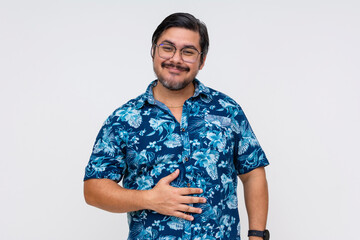 Content middle aged man in a floral Hawaiian shirt, rubbing his belly indicating fullness and...