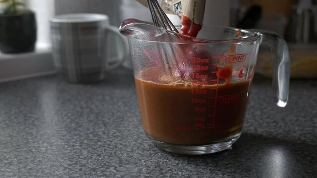 Stirring enchilada sauce in glass measure jar