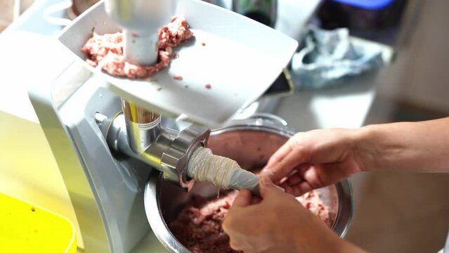 Chef puts the casing for stuffing sausages on the attachment for the meat grinder. High quality 4k footage