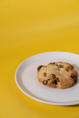 Cookies or biscuits with chocolate chips drops on a white plate. Yellow background. Great idea for breakfast