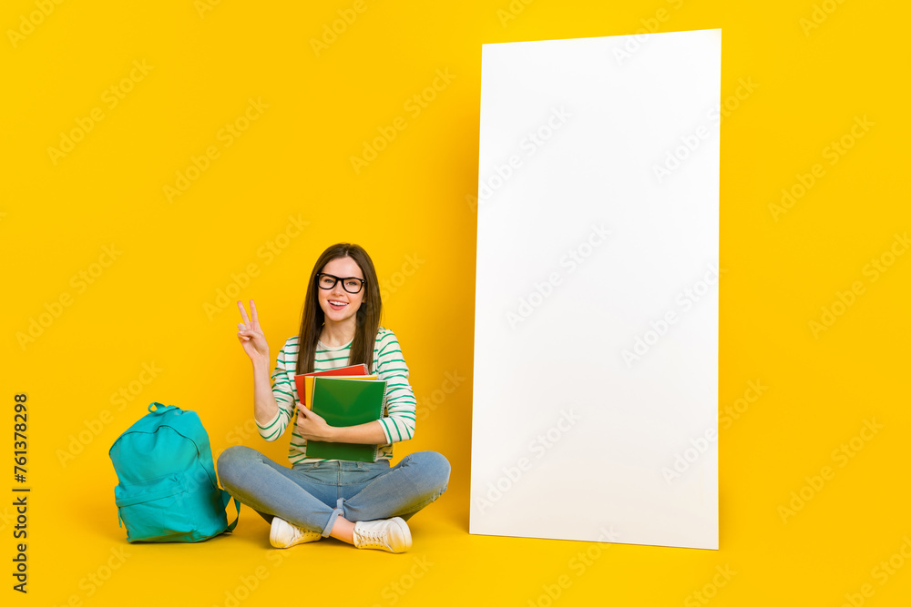 Sticker photo of charming adorable college student girl show v-sign say hello sit next to white board isolat