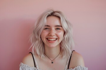 Young woman with silver blonde hair smiling on a pink background