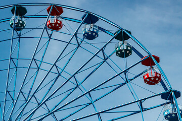 Colorful ride ferris wheel in motion in amusement park on sky background.