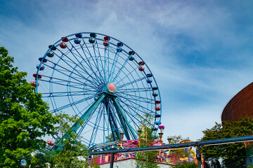 Colorful ride ferris wheel in motion in amusement park on sky background.