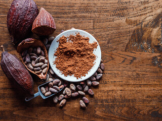Top view of Natural cocoa powder with brown cocoa beans and dry cacao pod  on a vintage wooden table.