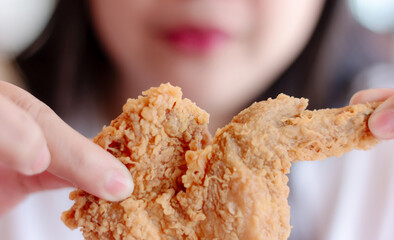 Woman eating fried chicken blurred background