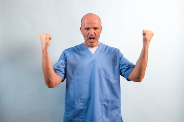 Portrait of a physiotherapist in a light blue coat with his arms raised in a symbol of triumph.