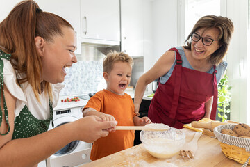 grandmother, mother and grandson cooking together having a great time