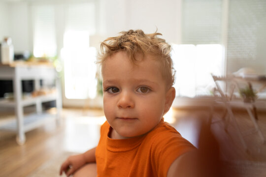 little boy taking a selfie at home with the phone portrait looking at the camera