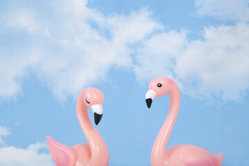 a pair of pink plastic swans against a background of blue summer sky