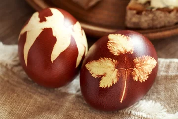 Fotobehang Close up of a brown Easter egg dyed with onion peels with a pattern of fresh leaves © Madeleine Steinbach