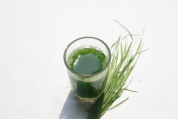 Wheatgrass juice on white background. Healthy organic green detox juice from grass of green...