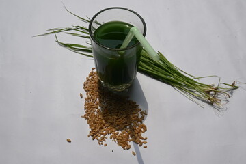 Wheatgrass juice on white background. Healthy organic green detox juice from grass of green...