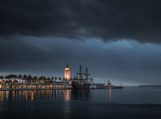 old Galleon anchored in a modern Marina next to a modern warship, in Malaga